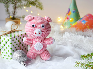 Pink pig, symbol of 2019 and gift on white background. Happy New Year and Merry Christmas card. Crochet toy for child. Handmade crafts on holiday with your own hands. DIY concept. Copy space