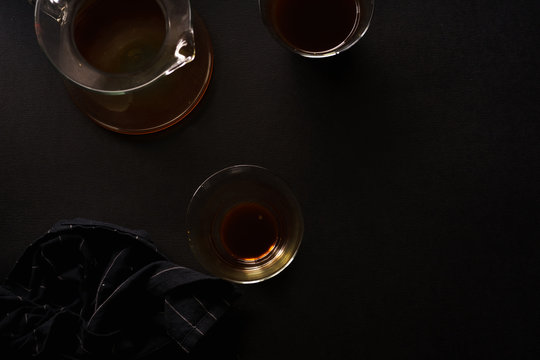 Pour over coffee in picther in two glasses on black background with black napkin. Overhead view