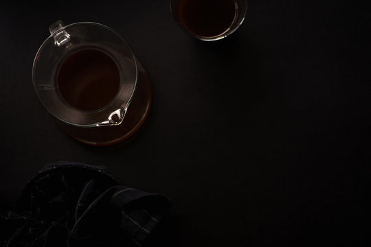 Pour over coffee in picther in two glasses on black background with black napkin. Overhead view