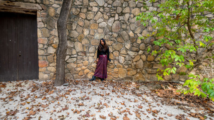 Woman in sarong standing on stage in stone amphitheater leaning against wall