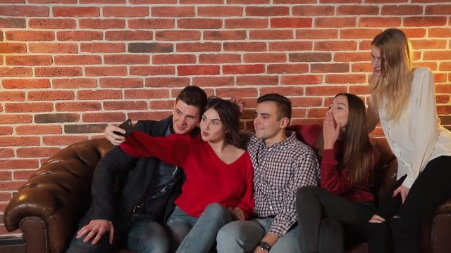 Cheerful friends taking selfie at the birthday party, good-looking young people celebrating important event after work in spacious flat