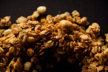 Overhead image of roasted granola laid in a form of a curve on black background. Design concept