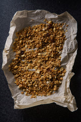 Top view of roasted granola with nuts, flakes and raisins on parchment paper. Close up texture