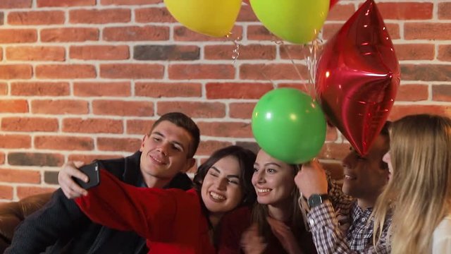 Cheerful friends taking selfie at the birthday party, good-looking young people celebrating important event after work in spacious flat