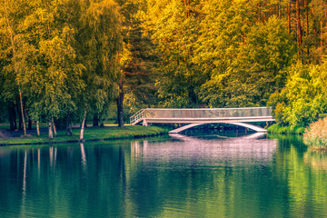 Old small white bridge over lake at sunny autumn day