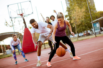 Group of multiethnic people  playing basketball on court