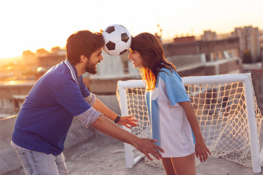 Couple balancing with a football between their heads