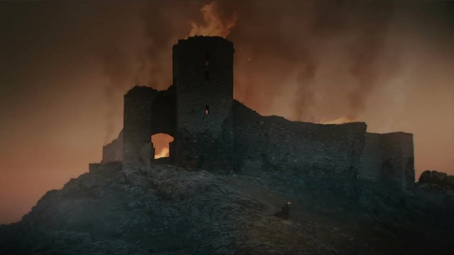 Fortress burning at sunset after medieval battle. 