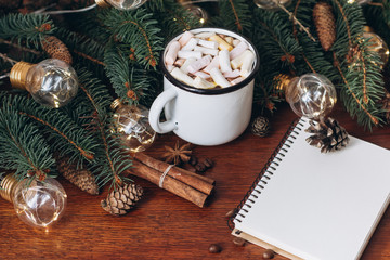 Chocolate or cocoa with marshmallow,  notebook and  garland on a wooden background.
