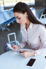 young businesswoman sitting in airport cafe and holding tickets