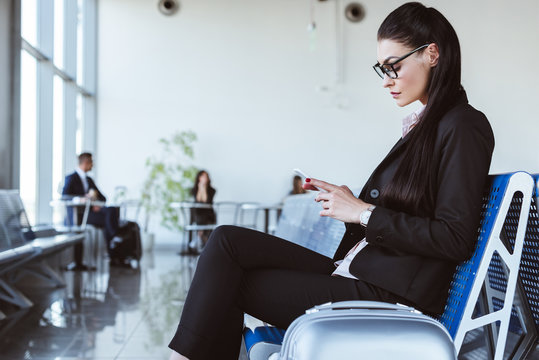 young businesswoman using smartphone at departure lounge in airport
