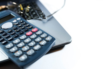 Eyeglass, pencil, calculator on laptop computer keyboard, business background image, space for text.