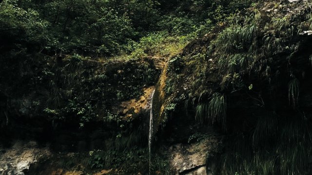 Cinematic aerial drone image of waterfall and a small pool deep in the rainforest jungle at Amboro National Park, Bolivia