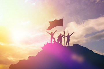 High achiever, silhouettes of three people holding on top of a mountain to raise their hands up. A...