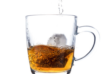 Brewing a tea bag in a transparent mug with sugar on a white background, a storm in a glass