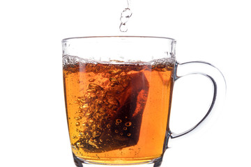 Brewing a tea bag in a transparent mug with sugar on a white background, a storm in a glass