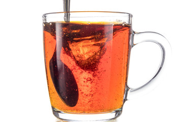 Dissolving a piece of sugar in tea in a transparent mug on a white background, a storm in a glass