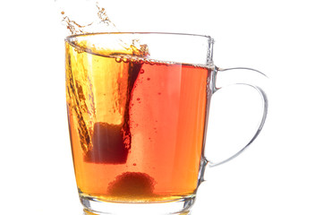 Dissolving a piece of sugar in tea in a transparent mug on a white background, a storm in a glass