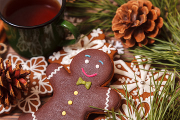 Christmas background. Tea in a metal green mug, traditional Christmas gingerbread, Christmas tree branches and cones on a wooden background close-up, top view