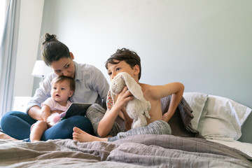 Mother Cuddling Children at Bed Time