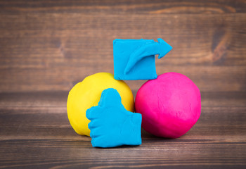 share and like hand icon from plasticine and multiple colorful balls on wooden background