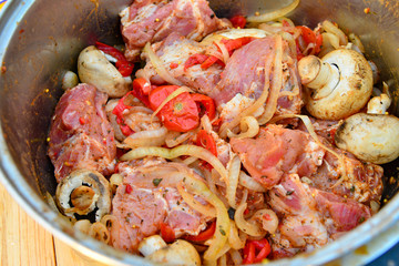 Raw meat in the marinade is in the pan, kebab with onions, mushrooms and meat.