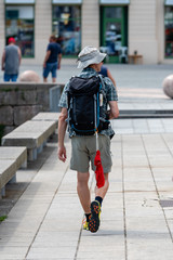 A man goes on the street with a backpack. Wear swimming trunks attached to the backpack. View from back.