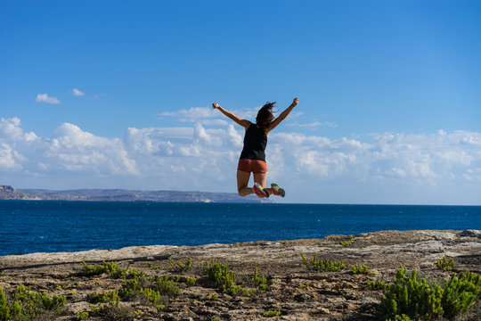 Femme sautant de joie face &agrave; la mer