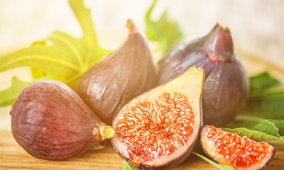 Whole figs and one fig sliced in half on top of a teak garden