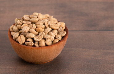 Bowl of Raw Green Coffee Beans on a Wooden Table