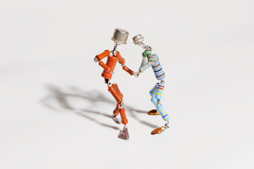 two funny small human figures, roughly welded  from resistors and transistors, dance together on a light background