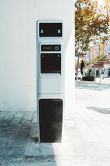 Outdoor power supply station of black and white colors for electric car charging; electric vehicle charging station for public usage in the shadow of Barcelona street, Spain