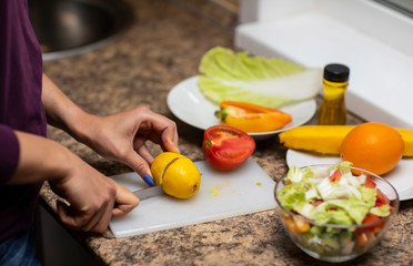 Female hand cuts vegetables for salad.