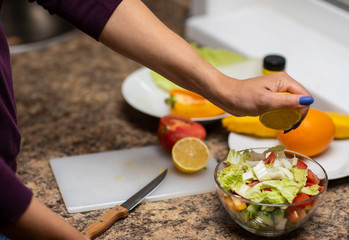 Female hand cuts vegetables for salad.