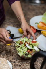 Female hand cuts vegetables for salad.