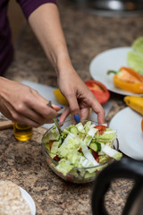 Female hand cuts vegetables for salad.