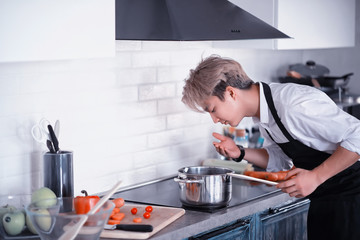 Asian cook in the kitchen prepares food in a cook suit