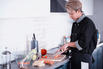 Asian cook in the kitchen prepares food in a cook suit