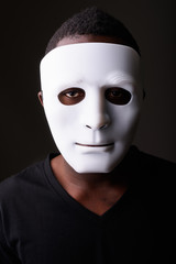 Portrait of young black African man in dark room wearing mask