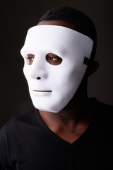 Portrait of young black African man in dark room wearing mask