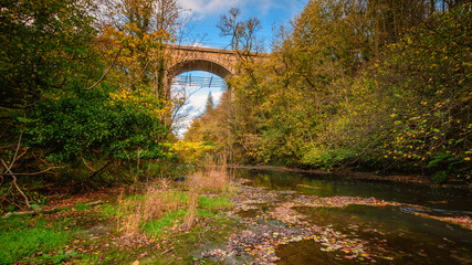 Fototapeta na wymiar Railway Viaduct over River Blyth, five arches hidden by trees in Plessey Woods Country Park, Northumberland, which sits on the north bank of the river