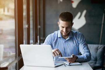 Young man drawing template for the web site associated with digital marketing, current trends and tendencies of UX / UI design. Businessman who rules his company remotely, like a freelancer