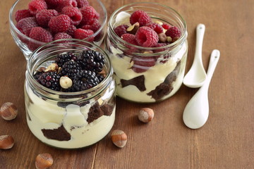 Dessert with chocolate biscuit, cream, hazelnut and fresh berries in glass jars, trifle