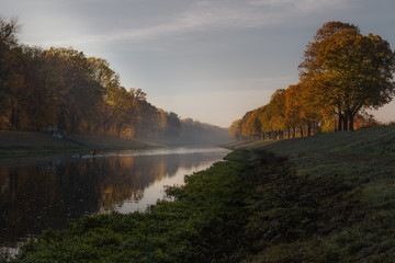 Naklejka na ściany i meble Kajak-Fahrer paddeln auf einem Fluss durch die Herbstlandschaft