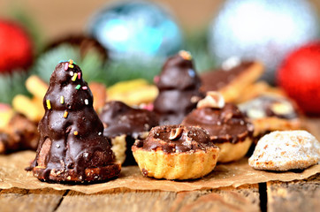 Detail of christmas sweets with different types of candy on baking paper and Christmas decorations in background