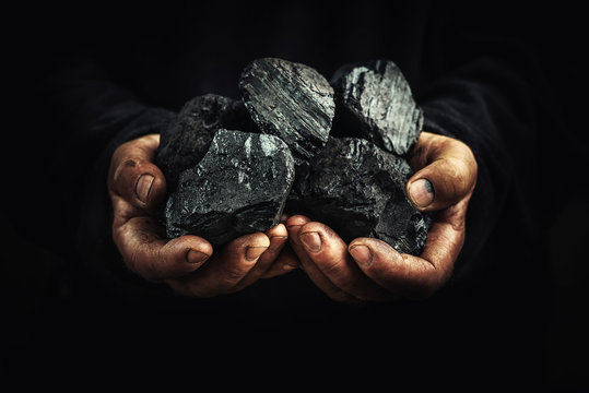 black coal in the hands, heavy industry, heating, mineral raw materials