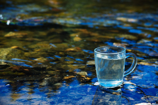 Glass Cup on the background of a pure mountain spring. The concept of clean water © malykalexa777