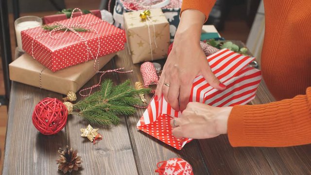 Holiday decor concept. Woman's hands tying christmas holiday handmade present in craft paper with twine ribbon. Making bow at xmas gift box. Creative hobby.