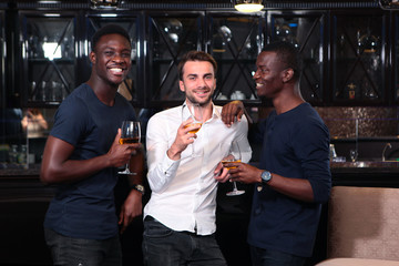Three guys resting in a cafe or restaurant. Different races together on vacation. The concept of celebration and fun. The concept of friendship of different nationalities.