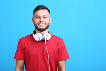 Young man with headphones on blue background